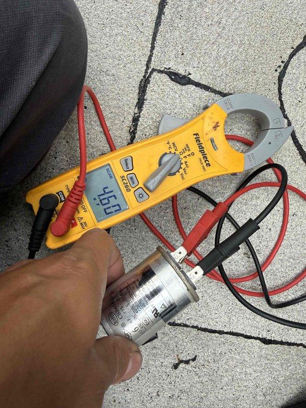 Replaced failed 6 microfarad capacitor in Bosch air conditioning unit. Tested new capacitor with digital meter to verify proper electrical specifications and confirmed system operation. Documented installation with photos showing capacitor testing and final placement on control board.