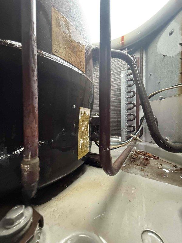 Responded to no cooling complaint at commercial facility. Upon arrival, conducted thorough inspection of rooftop unit that has experienced recurring issues despite previous clean and check service in March showing no problems. Performed comprehensive diagnostic evaluation of compressor, motor assembly, and refrigeration components. Inspected condenser coil fins for blockages or damage, examined electrical connections, and verified proper operation of all mechanical components. Documented equipment condition with photos showing compressor assembly, internal cabinet components, heat exchanger coils, and overall system condition. Unit showed signs of age and wear on various components including painted surfaces and manufacturer labels. System evaluation completed during tenant occupancy hours.