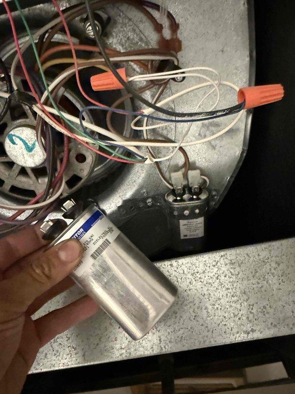 Responded to service call for thermostat malfunction at residential condo unit. Upon arrival, performed diagnostic assessment of HVAC system to identify root cause of thermostat issues. Inspection revealed the problem extended beyond the thermostat itself to the rooftop HVAC equipment, specifically affecting the air conditioning condenser unit. 

Accessed rooftop mechanical equipment and found weathered cylindrical condenser unit with visible signs of age and operational wear. Conducted electrical component testing and identified failed capacitor as primary cause of system malfunction affecting thermostat operation. Removed defective capacitor from blower motor assembly and replaced with new OEM-specification capacitor, ensuring proper electrical connections and secure mounting. Verified all wire connections, including color-coded wiring harness with appropriate wire nuts, and confirmed relay components were functioning correctly. 

Tested system operation following capacitor replaceme