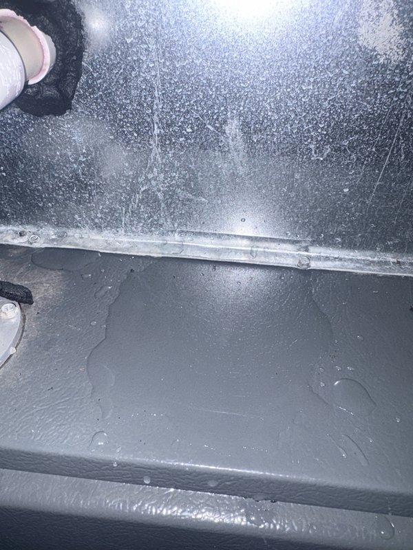 Responded to no cooling complaint on 18-19 year old residential AC system. Upon inspection, discovered extensive ice buildup on evaporator coil and interior air handler surfaces, indicating restricted airflow or low refrigerant charge. Documented frozen coil condition with photographs showing heavy frost accumulation on coil fins and surrounding components. Verified thermostat settings, checked air filter condition, and confirmed breaker status. System unable to provide adequate cooling due to icing condition preventing proper heat exchange. Recommended allowing unit to thaw completely before further diagnostics to determine root cause—either refrigerant leak requiring recharge or airflow restriction from dirty coil/blower issues. Given age of equipment, discussed system replacement options as alternative to repairs on aging unit approaching end of expected service life.