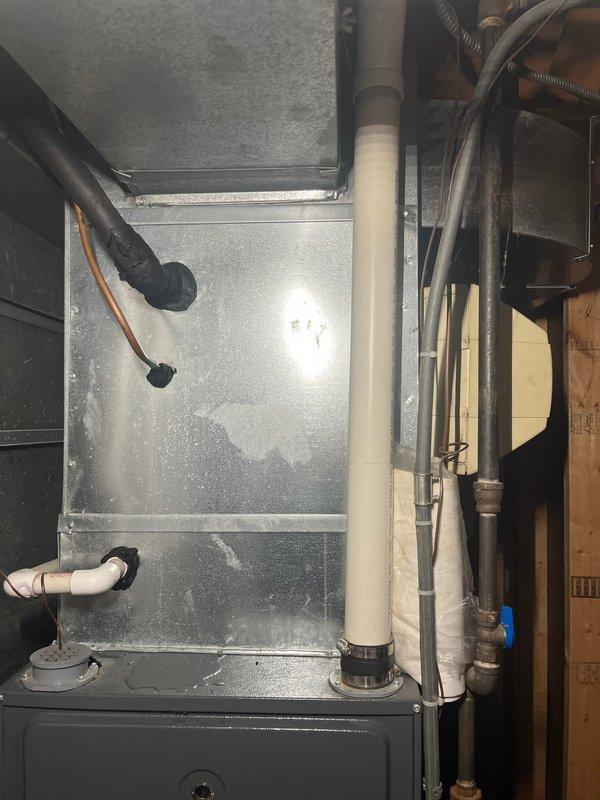 Completed full HVAC system replacement for residential property with 18-19 year old underperforming equipment. Removed existing furnace and air conditioning system and installed new York condenser unit on exterior concrete pad with proper refrigerant line set routing along foundation and up siding. Installed new indoor air handler in basement utility area with updated galvanized ductwork connections. Completed all necessary piping connections including copper refrigerant lines, PVC condensate drainage, and electrical disconnect installation. System tested and operational upon completion.