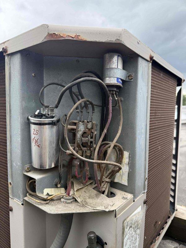 Completed commercial preventive maintenance inspection on rooftop HVAC unit originally installed in 1991. Verified proper operation following recent capacitor replacement, documented equipment condition with photos showing significant age-related deterioration including rust and corrosion on access panels and electrical components, and noted unit may require replacement evaluation in near future.