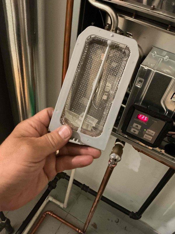 Responded to callback for tankless water heater displaying error code 12, same issue as previous day's service call. Upon arrival, inspected unit and discovered debris-clogged inlet filter screen causing flow restriction and triggering fault code. Removed and cleaned inlet filter assembly, cleared accumulated sediment from mesh screen, reinstalled filter, and reset system. Verified proper water flow through copper supply lines and confirmed unit operation with no error codes displayed. System restored to normal function.