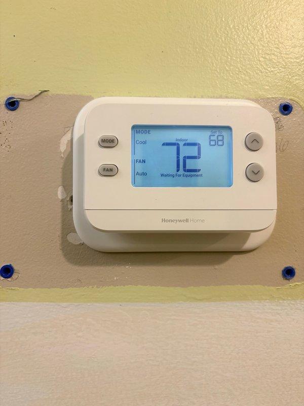 Responded to no cooling call and found Honeywell thermostat displaying "Waiting For Equipment" message while set to cooling mode at 68 degrees with indoor temperature at 72 degrees. Inspected outdoor condensing unit which showed significant weathering and rust staining on exterior cabinet, indicating extended outdoor exposure. Diagnosed communication failure between thermostat and outdoor unit, verified thermostat settings and wiring connections, and prepared replacement thermostat for installation to restore proper system operation.