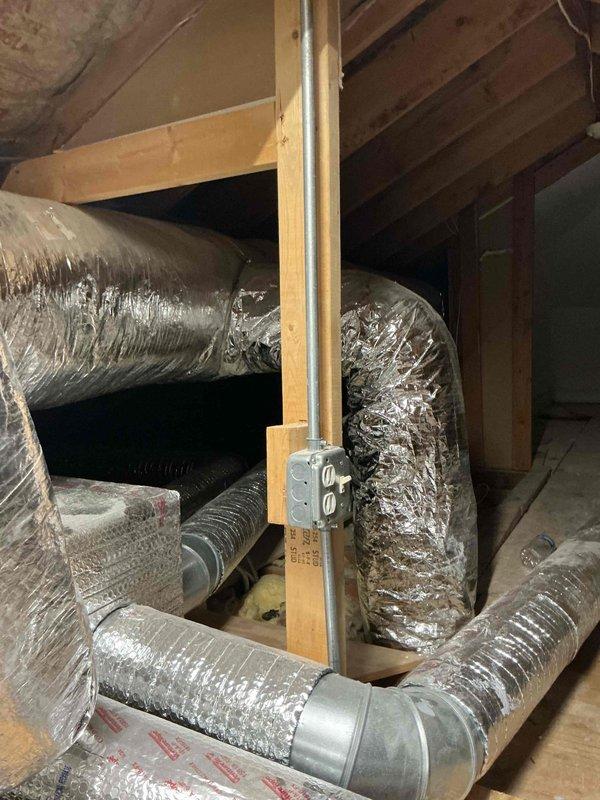 Responded to service call for AC not cooling evenly with water accumulation in safety drain pan. Upon arrival, inspected HVAC system installation including condensate drainage components and ductwork routing throughout attic space. Documented existing system configuration showing PVC condensate drain line with visible staining and discoloration, copper refrigerant lines, and flexible aluminum ductwork distribution system. Collected equipment information for new customer account and photographed installation for service records.