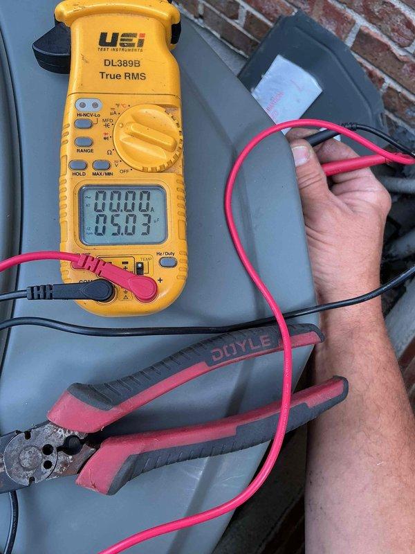 Performed warranty inspection on outdoor HVAC unit. Accessed interior compartment and identified heavily corroded capacitor with significant rust on top cap and terminals. Evaluated electrical connections and wiring configuration throughout unit, noting multiple wire bundles secured with proper routing. Used digital multimeter to test capacitor functionality, obtaining diagnostic readings to determine component condition. Documented unit condition with photographs showing weathered components consistent with extended outdoor exposure. Prepared to return with blower motor for potential warranty replacement if needed, pending further diagnostic evaluation and concurrent preventative maintenance service.
