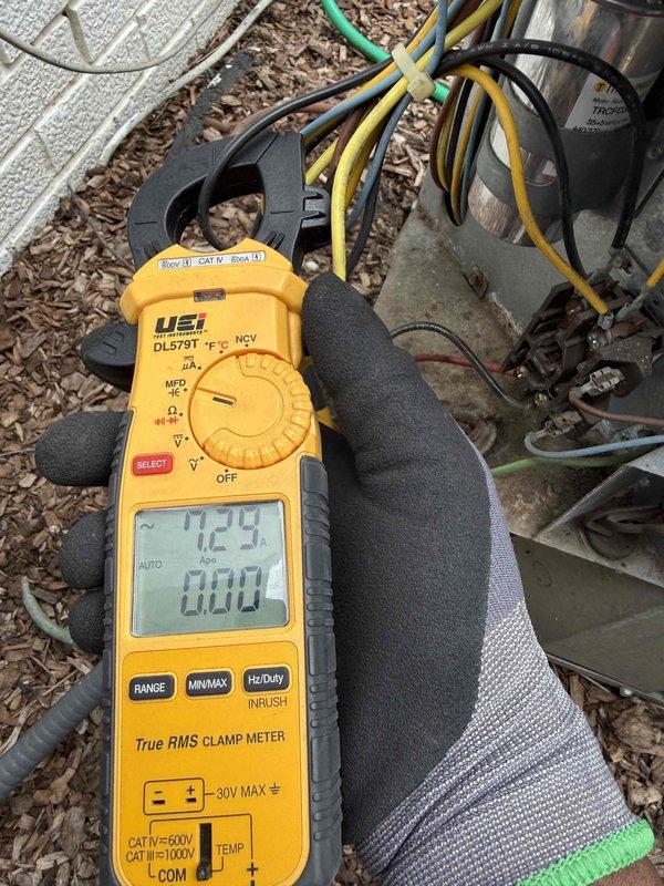 Responded to no cooling call on outdoor HVAC unit. Upon arrival, performed electrical diagnostics using clamp meter to measure amperage draw and verify compressor operation. Inspected outdoor condensing unit components including dual capacitors (GE and TITAN PRO brands) and contactor assembly. Found 12.9 amp reading during testing, indicating potential issue with compressor or capacitor performance. Evaluated all electrical connections, wiring integrity, and component conditions to determine root cause of cooling failure.