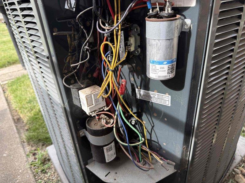 Completed spring clean and check on outdoor air conditioning system per comfort plan maintenance agreement. Performed comprehensive inspection of condenser unit components including dual-run capacitor, contactor, and compressor assembly, verified all electrical connections secure, and documented equipment condition with photos showing GE capacitor rated at 370VAC and all wiring in proper working order.