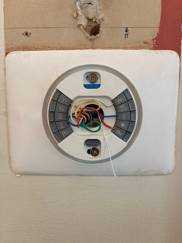 Installed new thermostat wiring and mounted thermostat unit on existing wall location. Connected multi-conductor thermostat cable to terminal block, including Y1, Y2, G, O/B, Rc, Rh, W1, W2, and C terminals with appropriate color-coded wires for proper HVAC system communication and control.