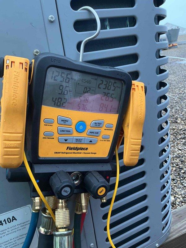 Identified noncondensables in the R-410A refrigerant system during diagnostic testing with manifold gauges. Recovered existing refrigerant charge and performed nitrogen purge throughout the system to remove contaminants. Removed and cleaned metering piston, then performed gravity-assisted nitrogen blow-through of refrigerant lines from rooftop condenser unit down to air handler. Reinstalled piston and installed new filter drier on 3/8" liquid line at air handler. Completed pressure test to verify system integrity, evacuated system to proper vacuum levels, and recharged with fresh R-410A refrigerant to manufacturer specifications. Verified all operating parameters and system performance upon completion.