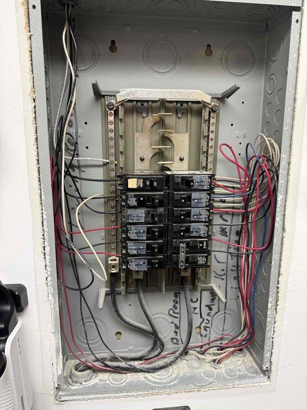Responded to callback for burnt electrical odor in laundry room following breaker trip. Inspected electrical panel and identified laundry circuit breaker that had tripped. Examined panel for signs of overheating, damaged wiring, or loose connections at breaker terminals and found no visible damage or scorching. Documented panel condition with photographs showing all circuit breakers, wiring connections, and specifically the laundry outlet circuit in question for reference and safety verification.
