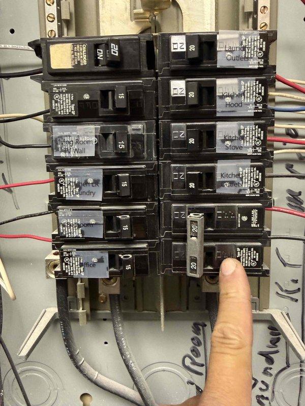Responded to callback for burnt electrical odor in laundry room following breaker trip. Inspected electrical panel and identified laundry circuit breaker that had tripped. Examined panel for signs of overheating, damaged wiring, or loose connections at breaker terminals and found no visible damage or scorching. Documented panel condition with photographs showing all circuit breakers, wiring connections, and specifically the laundry outlet circuit in question for reference and safety verification.