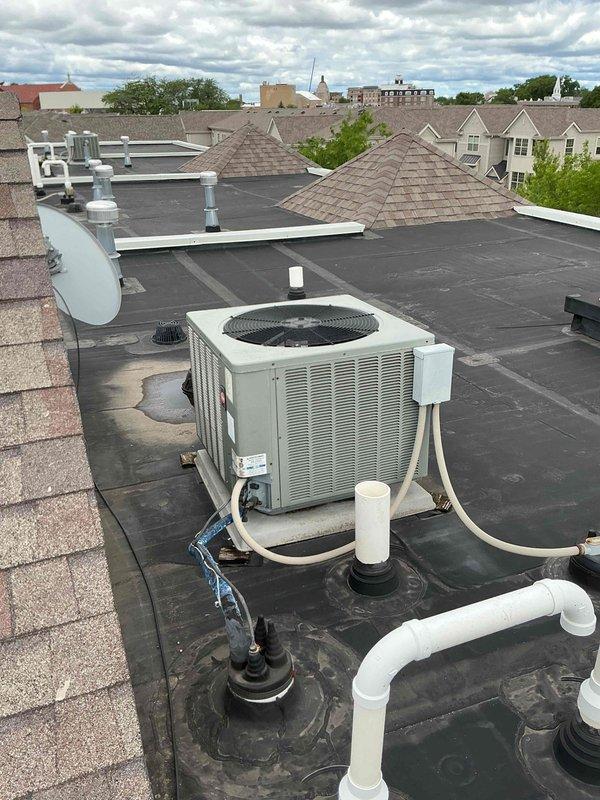 Performed AC coil cleaning service on rooftop-mounted condenser unit at multi-unit residential property. Thoroughly cleaned evaporator and condenser coils to restore optimal heat transfer efficiency and system performance. Unit documented with photographic records showing completion of work on flat membrane roof with proper drainage considerations noted.