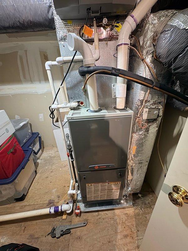 # Replace Heat Exchanger For Attic Furnace

Replaced failed heat exchanger on residential Trane furnace system located in attic space. Ordered replacement heat exchanger component for delivery and installation. System verified operational with thermostat displaying proper heating function at time of service call, set to 78°F with current indoor temperature reading of 76°F at 10:36 AM. Furnace installation includes proper PVC venting configuration for intake and exhaust, gas supply lines with shutoff valves, and insulated flexible ductwork distribution system. Unit positioned on concrete surface with appropriate clearances maintained for service access and safety compliance.