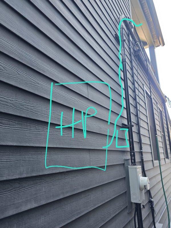 Completed site visit to confirm and document heat pump location for electrical contractor coordination. Photographed exterior wall showing existing electrical conduit routing and junction box placement, then marked proposed heat pump installation location on building siding to clearly indicate positioning requirements for electrical rough-in work.