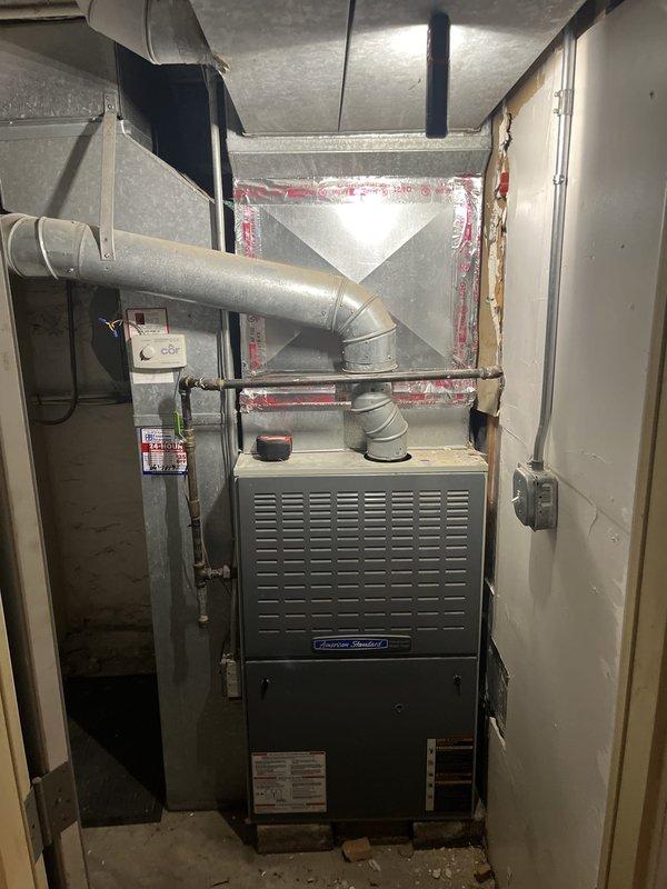 Performed estimate consultation for furnace replacement on 20-year-old American Standard heating system. Previous contractor identified hairline fracture in heat exchanger requiring unit replacement. Documented existing equipment configuration including furnace unit, ductwork connections, and humidifier system with photographs of data plates and current installation for replacement specifications.