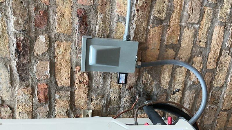Completed no-charge callback to install surge protector on HVAC system mounted to exterior brick wall with deteriorated mortar. Installed gray electrical enclosure with conduit routing and verified proper wiring connections to equipment. Extended PVC flue piping using two couplings, two long sweep 90-degree elbows, and two street 45-degree fittings per specifications. Documented installation with photos showing completed surge protection device, electrical box mounting, and existing line set with insulation.