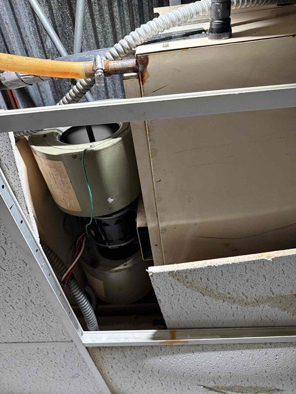 Responded to water leak concern related to air conditioning system. Upon inspection, accessed air handling unit and examined condensate drain system components. Found condensate line connection point at drain pan with visible signs of previous water overflow and staining. Inspected blower motor assembly and internal components for proper operation. Checked copper refrigerant line connections and condensate drain routing. Verified drain pan condition and cleared condensate line obstruction to restore proper drainage flow. Tested system operation to confirm water is draining correctly and leak has been resolved.