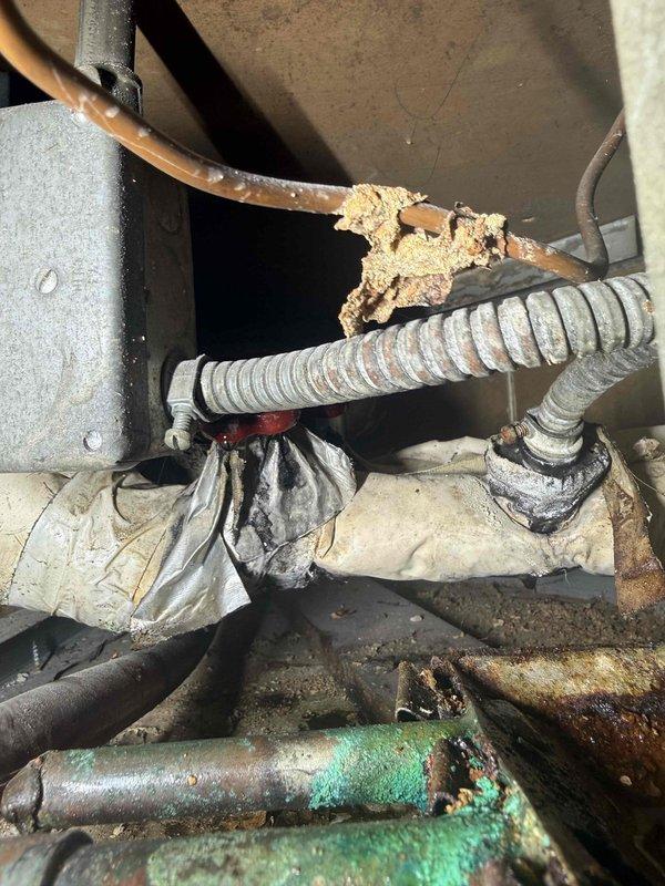 Responded to no cooling complaint with reported water leakage from air conditioning system. Upon inspection, discovered severely corroded copper refrigerant lines with significant deterioration and crusty buildup indicating long-term moisture exposure and potential refrigerant leak. System showed multiple signs of aging including oxidized copper piping with green verdigris formation and deteriorated insulation wrapping. Measured supply air temperature at floor register reading 50°F, confirming inadequate cooling performance. Documented extensive corrosion throughout refrigerant line assembly and deteriorated system components consistent with unit age exceeding 10 years. Photographed corroded refrigerant lines and recorded airflow measurements for diagnostic documentation.