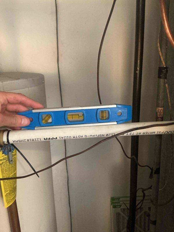 Responded to return visit for ongoing basement water leak with suspected condensate line backup. Upon arrival, inspected HVAC system and associated plumbing components in mechanical room. Verified proper pitch and drainage of PVC condensate line using level to ensure gravity flow. Examined water heater, ductwork connections, and surrounding plumbing infrastructure for potential leak sources. Documented equipment conditions and plumbing configuration with photos. All equipment information recorded for service records.