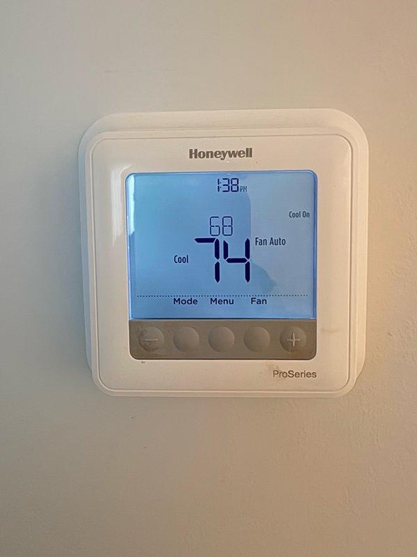 Responded to no cooling complaint on second floor air conditioning system. Upon arrival, verified thermostat was properly set to cooling mode at 68°F with system actively running and displaying "Cool On" status. Performed diagnostic inspection of outdoor condensing unit, removing access panel to examine internal components including capacitor, electrical connections, and control wiring. All electrical connections were secure with no signs of damage or loose terminals. Capacitor appeared in good physical condition with proper wire terminations on HERM, FAN, and COM terminals. Verified system operation and airflow at thermostat location showing 74°F ambient temperature with unit actively cooling.