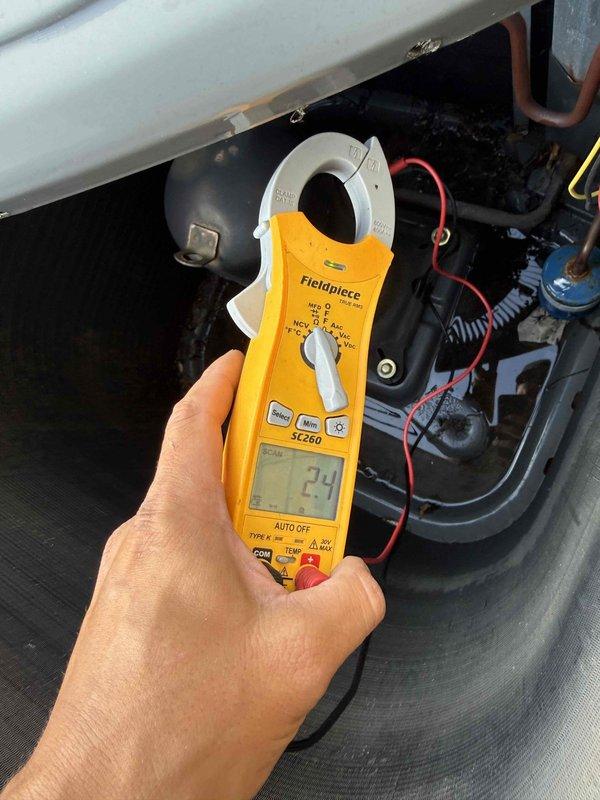 Responded to no-cooling call at residential property with Goodman condensing unit. Upon arrival, performed diagnostic evaluation of system using clamp meter to measure electrical parameters. Tested amperage draw, verified power supply to outdoor unit, and inspected capacitor, contactor, and associated wiring connections. Documented equipment information and captured diagnostic readings showing 2.9 measurement on multimeter during troubleshooting process. Identified issue affecting tenant comfort and provided repair options to property owner.