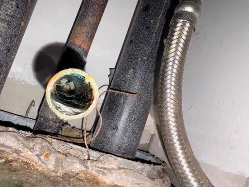 Responded to no cooling complaint with reported water leakage from indoor air handler unit. Upon arrival, found system shut down by customer due to active leak. Inspection revealed significant corrosion around drain pan connections and evidence of standing water overflow from clogged condensate drain system. Primary drain line showed heavy buildup and blockage, causing water to back up into the drain pan. Cleared condensate drain obstruction using appropriate methods and verified proper drainage flow. Noted corrosion on drain pan components and electrical connections in the affected area, indicating prolonged moisture exposure. Checked air filter condition and found it to be adequate. Verified thermostat settings were correct for cooling operation. Tested system operation after clearing drain blockage and confirmed unit cooling properly with no active leaks. Documented equipment information and photographed corroded components for customer records. Discussed preventive maintenance opti