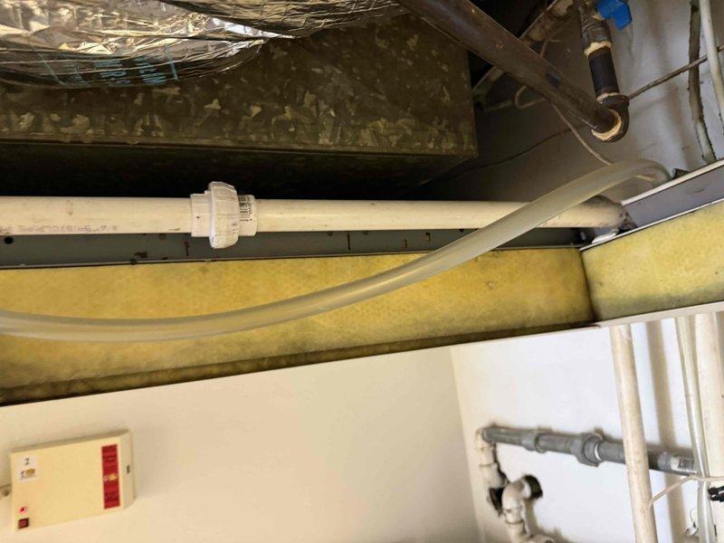 Responded to emergency water leak call at commercial property. Upon arrival, inspected HVAC equipment and associated plumbing infrastructure in mechanical space. Located source of water leak in vicinity of PVC piping and ductwork system. Documented existing conditions with photographs showing overhead utility space with horizontal PVC pipe runs, fiberglass insulation, metallic ductwork, and associated mechanical components. Assessed situation and contacted office to report findings and initiate approval process with property management for necessary repairs.