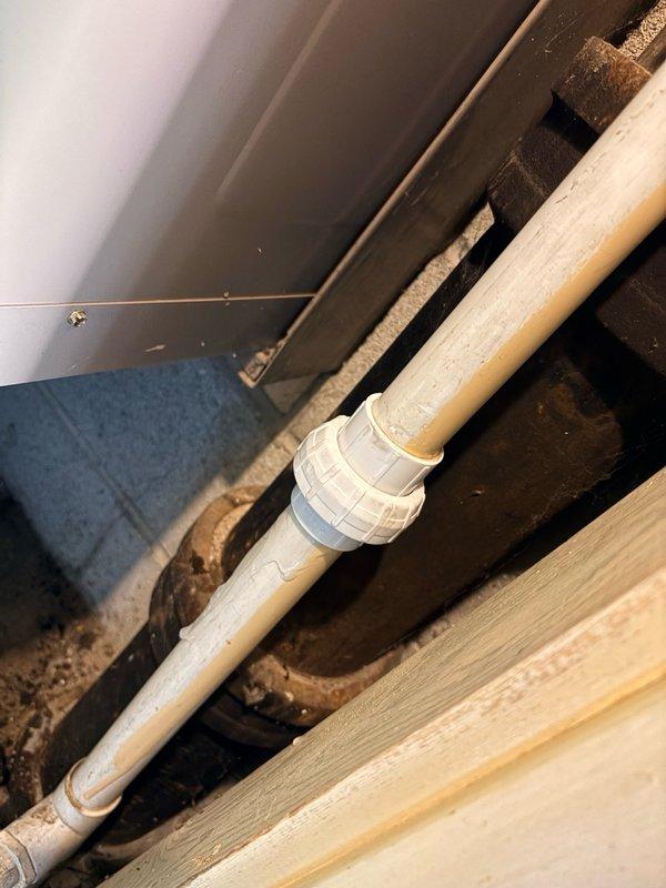 Responded to water leak call in basement utility area. Upon inspection, found evidence of moisture damage on concrete floor with significant staining and discoloration patterns indicating previous water intrusion. Examined PVC drainage piping system and connections, including white coupling joints and elbow fittings connecting to copper piping. Assessed condition of plumbing infrastructure, noting older metal components showing signs of corrosion and oxidation in proximity to newer PVC installations. Documented existing conditions with photographs showing water damage patterns, pipe routing, and structural elements. Communicated findings to property owner regarding association responsibility and reimbursement procedures. Collected standard dispatch fee and explained diagnostic process, flat rate repair options, and available customer programs. Recorded all equipment information for service records.