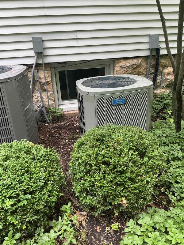 Responded to no cooling complaint on second floor unit with indoor temperature at 94 degrees. Upon arrival, verified thermostat set to 72 degrees in cooling mode with system blowing warm air. Performed diagnostic evaluation of outdoor condenser unit and indoor air handler. Inspected refrigerant lines, electrical connections, and compressor operation. System exhibited signs consistent with aging equipment over 10 years old. Documented equipment information and captured photos of outdoor unit installation showing dual condenser setup with proper clearances and electrical disconnects. Completed thorough assessment and discussed repair options and replacement considerations given age of equipment.