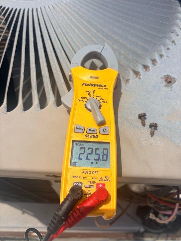 Responded to continued no cooling complaint in commercial office space on return visit. Upon arrival, verified thermostat settings and confirmed system was set to cooling mode with display reading 83°F. Performed diagnostic testing of air conditioning unit using clamp meter to measure electrical parameters at condenser coil. Observed evidence of corrosion and weathering on exterior housing panel and heat exchanger fins. Measured voltage reading of 225.8V at equipment. Documented thermostat operation with lockbox cover in place and captured electrical measurements during testing. Coordinated with office for approval process prior to proceeding with repairs, as tenant is responsible for HVAC maintenance at this property.