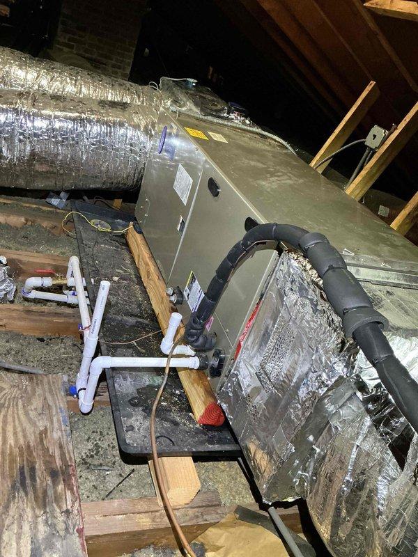 Responded to callback for condensate drain line obstruction preventing proper drainage. Upon inspection in attic space, located air handler unit and associated condensate drainage system with white PVC piping assembly. Verified drain pan was collecting water but line was not flowing properly. Cleared blockage from condensate line, tested drainage flow, and confirmed system was draining freely. Monitored unit through complete cooling cycle to ensure proper condensate removal and verified no water accumulation in drain pan.
