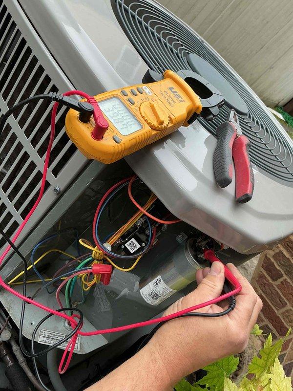 Completed comprehensive clean and check maintenance service on two residential air conditioning systems per comfort plan agreement. Performed electrical diagnostics on outdoor condensing unit using digital multimeter to verify proper voltage and amperage readings across capacitor and electrical components. Tested all wire connections including color-coded HVAC wiring harness to ensure secure terminations and proper electrical function. Inspected condensing unit positioned on concrete pad, noting standard installation with electrical disconnect box and conduit properly mounted to exterior brick wall. Verified adequate clearance around unit and proper drainage line placement. Both systems operating within manufacturer specifications with no immediate repairs required.