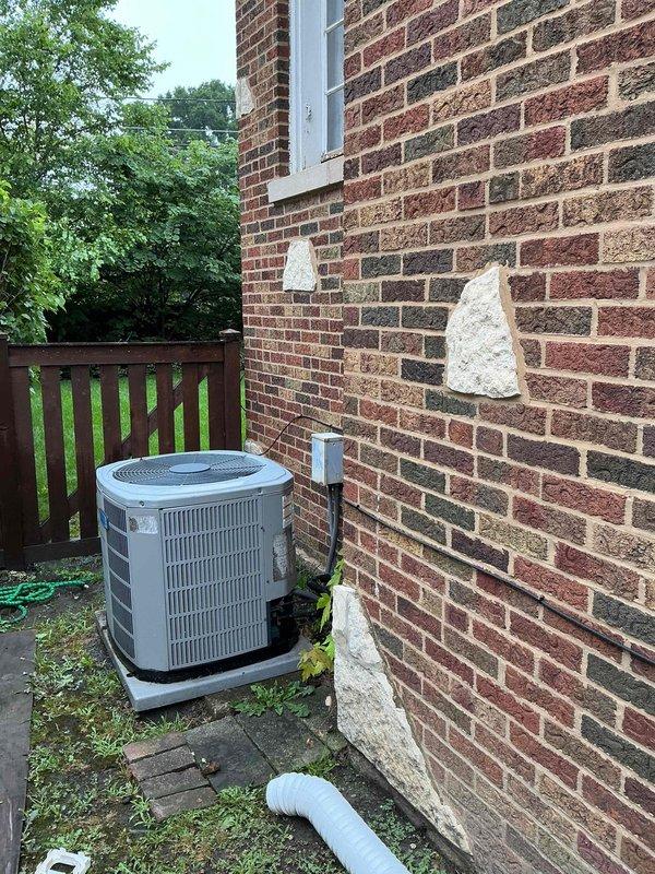 Completed comprehensive clean and check maintenance service on two residential air conditioning systems per comfort plan agreement. Performed electrical diagnostics on outdoor condensing unit using digital multimeter to verify proper voltage and amperage readings across capacitor and electrical components. Tested all wire connections including color-coded HVAC wiring harness to ensure secure terminations and proper electrical function. Inspected condensing unit positioned on concrete pad, noting standard installation with electrical disconnect box and conduit properly mounted to exterior brick wall. Verified adequate clearance around unit and proper drainage line placement. Both systems operating within manufacturer specifications with no immediate repairs required.