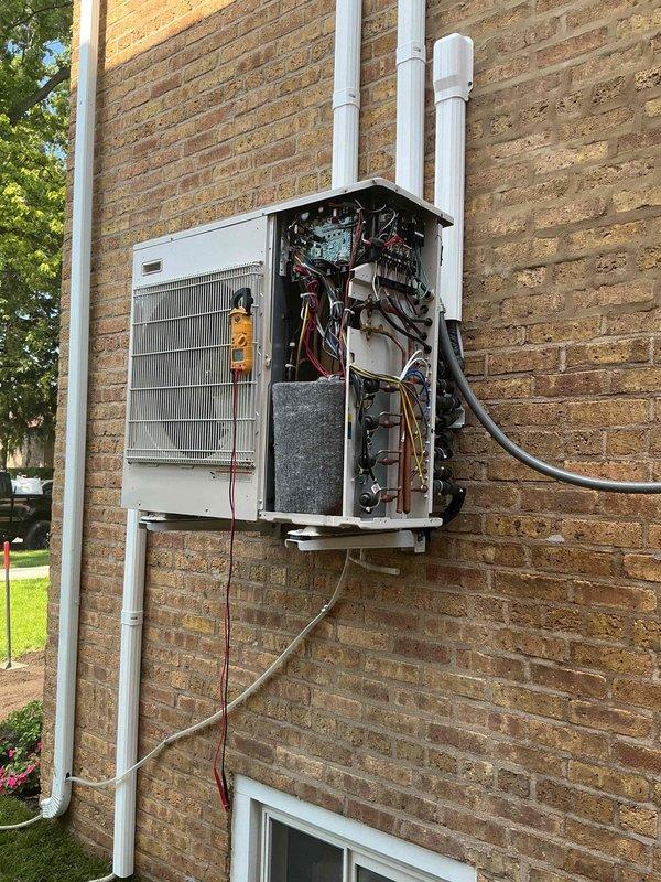 Responded to a complete system failure on a 2-year-old Haier multi-zone ductless mini-split system with four wall-mounted indoor units and an outdoor condensing unit mounted approximately 5-6 feet above ground level. Upon arrival, confirmed no power to any indoor units and no operation of outdoor unit. Accessed outdoor unit by removing front service panel and performed diagnostic inspection of internal components including control board, wiring connections, and electrical circuits. Photographed equipment condition and internal components showing circuit boards, wiring harnesses, copper refrigerant lines, and condensate drainage system for documentation purposes. System experienced sudden failure with no warning indicators or unusual sounds prior to shutdown, suggesting potential electrical or control board failure requiring further diagnosis and component replacement.