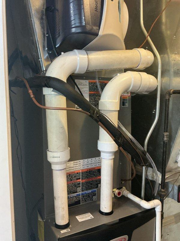 Completed final connections on new HVAC system installation, including flue pipe connections, gas line hookup, and initial furnace startup. All PVC venting, copper refrigerant lines, condensate drainage, and electrical connections were verified for proper operation, with system successfully fired up and confirmed operational.
