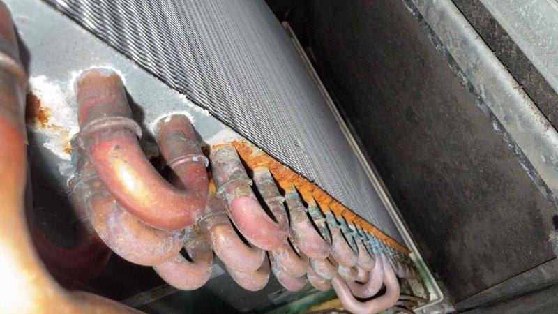 Responded to callback for AC unit not cooling after previous day's service where refrigerant and sealant were added. Upon inspection, discovered significant refrigerant leak at evaporator coil. Used UV light and fluorescent dye to confirm active leak at corroded copper U-bend connections. Found heavy corrosion on refrigerant lines with frost accumulation indicating ongoing refrigerant loss. Documented findings with photos showing compromised coil assembly requiring replacement under warranty.