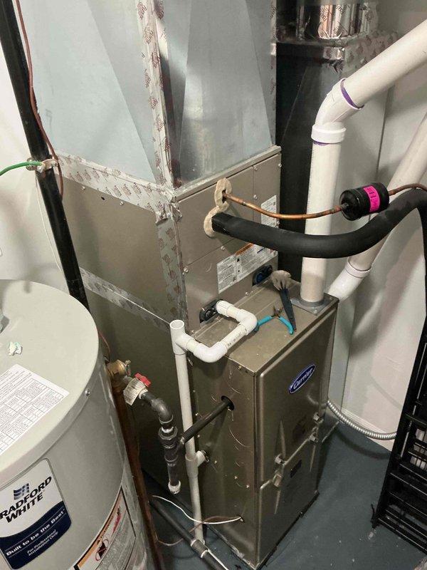 Responded to service call for excessive condensation on 2-year-old residential air conditioning system. Upon arrival, performed visual inspection of outdoor condensing unit and indoor HVAC components including furnace and associated refrigerant lines. Evaluated insulation integrity on copper refrigerant tubing, checked for proper drainage from condensate system, and inspected all accessible ductwork and piping connections. Documented system configuration with photographs showing both indoor air handler installation with PVC condensate drain lines and outdoor condensing unit positioned on concrete pad in landscaped area. Assessed overall system operation and provided customer with findings regarding condensation concerns.