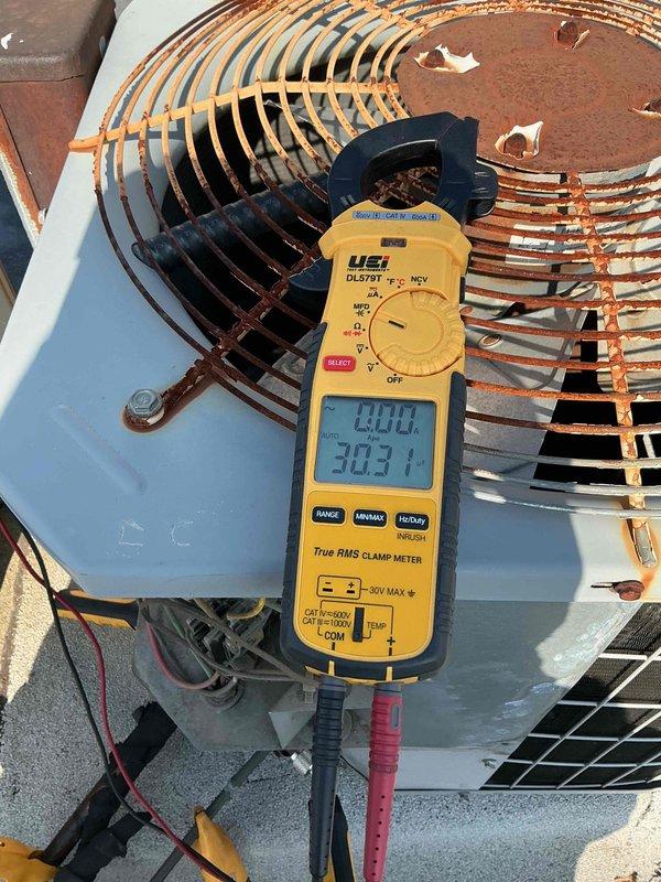 # HVAC Tune-Up Completed

Performed comprehensive tune-up on rooftop air conditioning system. Conducted electrical diagnostics using clamp meter, recording voltage and amperage readings to verify proper compressor operation at 303.1V and 13.001A. Inspected outdoor condensing unit, noting significant rust and corrosion on copper coil fins and aluminum fins throughout the unit, though system remained operational. Documented equipment condition including weathered exterior casing, deteriorated paint, and rust staining on associated metal housing panels. Verified refrigerant line connections and overall system functionality. Unit continues to operate despite visible aging and outdoor exposure damage.