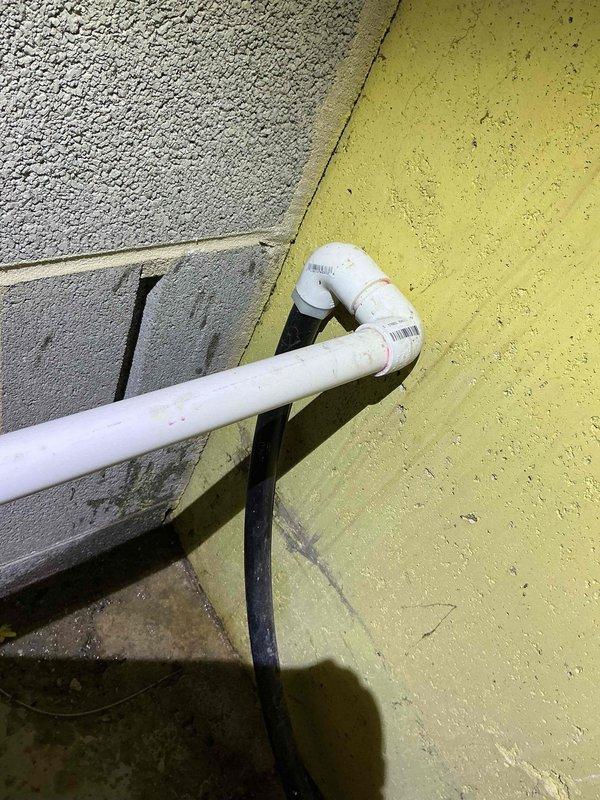 Responded to service call for air conditioning system leaking excessive water. Upon inspection, verified Bryant Evolution Connex system with thermostat operating in cooling mode at 66°F setpoint. Examined exterior condensate drain line where PVC discharge pipe exits building through stucco wall, confirming proper drainage flow and clearing any blockages to resolve water leak issue.