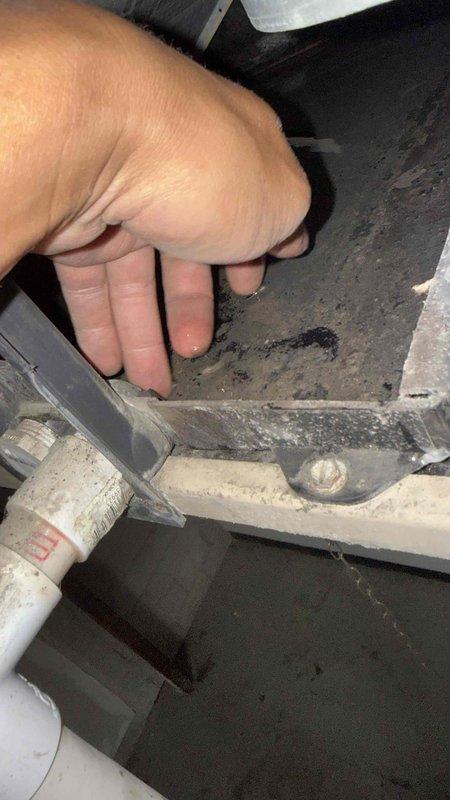 Responded to commercial water leak call at vacant warehouse unit where building engineer reported pronounced leak from corner requiring bucket placement. Upon arrival, accessed facility and inspected warehouse area with exposed ceiling-mounted HVAC equipment and air handling units. Located source of water accumulation and examined affected HVAC unit, documenting significant dirt and debris buildup on internal surfaces and condensate drainage components. Inspected PVC condensate drain line and mounting brackets showing signs of blockage or drainage issues causing water overflow. Photographed equipment condition and leak source for documentation purposes. Advised that condensate drain system requires cleaning and proper drainage restoration to resolve active leak condition.