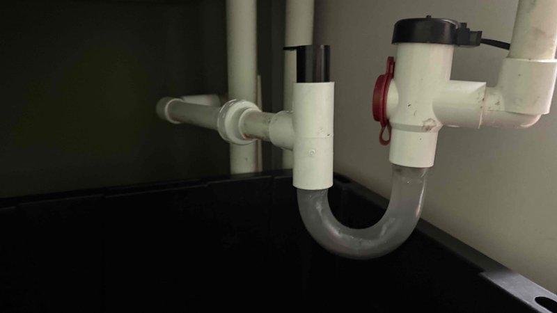 Responded to water leak call originating from HVAC unit. Upon inspection, identified leak source in drain line assembly beneath air handler. Examined condensate drain system including P-trap configuration and associated PVC drainage components. Verified air filter condition and checked return air vent housing for moisture intrusion. Inspected condensate pump assembly with reservoir and confirmed proper drainage pathway. Documented plumbing configuration and HVAC connections to determine leak was related to building plumbing system rather than HVAC equipment malfunction.
