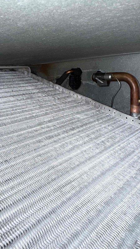 Responded to water leak complaint and performed diagnostic inspection of HVAC air handler system. Upon visual examination, inspected evaporator coil, refrigerant lines, and condensate drainage system for signs of moisture intrusion or leakage. Documented equipment condition with photographic evidence showing evaporator coil assembly, copper refrigerant lines with insulation, and air handler cabinet. Assessed condensate drain line routing and overall unit condition in mechanical room environment.