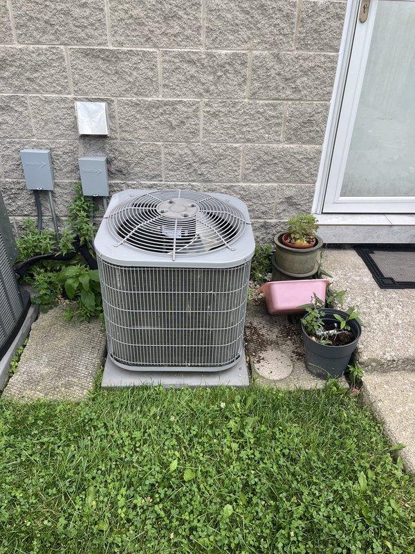 Performed comprehensive HVAC system evaluation for replacement estimate on residential property with existing 2015 furnace and 3-4 year old air conditioning system. Customer reported weak airflow throughout home despite recently replacing filter and maintaining clean evaporator coil. Conducted thorough inspection of outdoor condensing unit positioned on concrete pad adjacent to building exterior, noting cylindrical configuration with protective fan grille and standard vertical fin arrangement. Examined indoor furnace and air handler installation located in basement utility area, documenting existing ductwork configuration with galvanized metal supply plenum and associated copper refrigerant lines with insulation. Assessed overall system performance and identified need for ductwork evaluation and potential modifications to address inadequate airflow concerns. Documented equipment specifications, installation conditions, and mechanical room layout with reflective insulation barriers. Pro