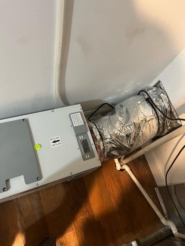 Installed E100 whole-home dehumidifier in basement mechanical room, replacing existing shelving. Ran 10" ductwork with two supply registers—one through wall near laundry room and one by treadmill area—to distribute conditioned air throughout basement and upper levels. Unit features automatic humidity control with programmable settings down to 45% RH, hourly air sampling capability, and independent operation. Installation includes proper leveling, electrical connection to control panel, and metallic flex duct with reflective insulation. System provides dual benefit of dehumidification and passive heating from heat of compression, improving overall comfort in conditioned spaces.