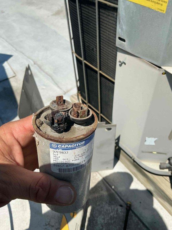 Responded to no cooling complaint on rooftop HVAC unit. Upon arrival, verified thermostat was set to cooling mode and system was calling but unit failed to operate. Performed visual inspection of outdoor condensing unit and found accessible electrical components. Removed access panel to electrical compartment and conducted diagnostic testing of starting components.

Identified failed dual run capacitor with severe corrosion and oxidation on terminals and connection points. Capacitor showed visible rust buildup and deterioration consistent with age and weather exposure on rooftop installation. Tested capacitor with multimeter and confirmed readings were out of manufacturer specifications, preventing compressor and condenser fan motor from starting properly.

Removed defective capacitor and replaced with new OEM-equivalent dual run capacitor rated to manufacturer specifications. Secured all wire connections to new capacitor terminals ensuring proper color-coded wiring configuration. Veri