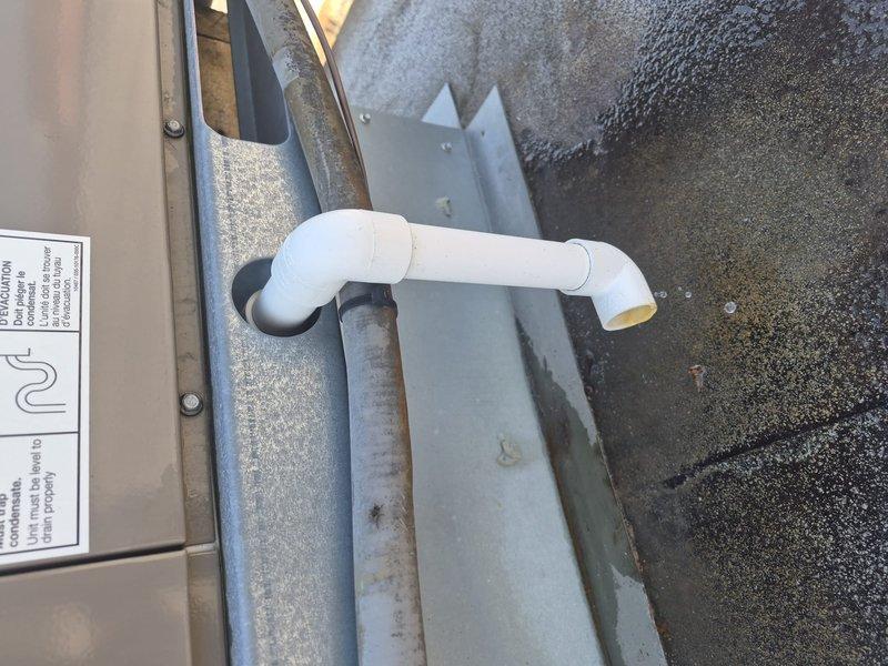Responded to service call for commercial ice cream shop experiencing inadequate cooling performance. Upon inspection, found evaporator coil with significant corrosion and oxidation on copper refrigerant lines, indicating system age and possible refrigerant line degradation. Observed corroded brass fittings at connection points and discolored metal fins with dirt accumulation affecting heat transfer efficiency. Exterior condensate drain system showed proper drainage function with weathered galvanized drain pan and PVC discharge line intact. Documented equipment condition showing normal wear patterns consistent with extended service life and recommended monitoring for potential refrigerant leaks due to copper line deterioration.