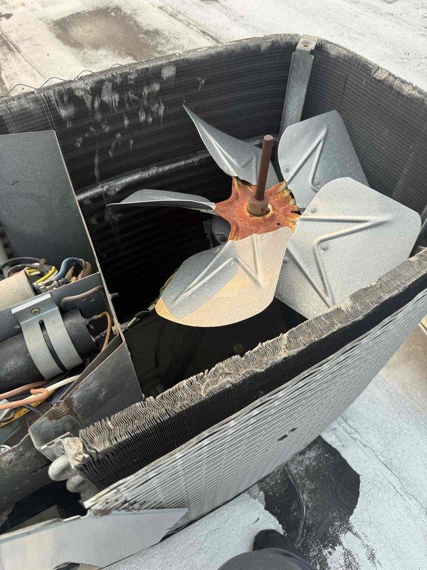 Responded to no cooling complaint for south side AC unit 1704. Upon inspection, found rooftop condenser unit with visible corrosion on fan motor hub and mounting hardware indicating equipment age and weathering. Assessed condenser fan assembly and motor operation. Performed diagnostic temperature measurements on evaporator coil using digital thermometer with probe attachments. Evaluated coil condition and system performance. Documented equipment condition with photos showing fan assembly deterioration and coil measurements for estimate preparation.