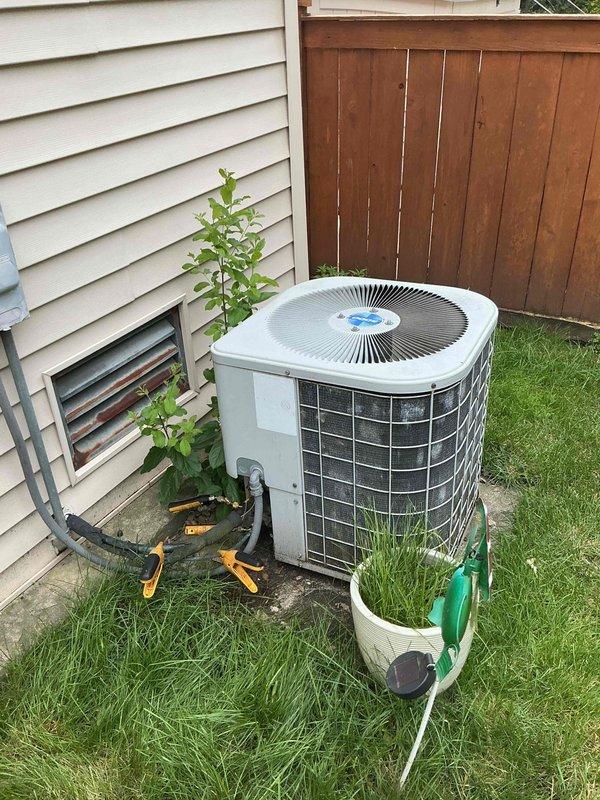 Completed spring preventative maintenance on residential air conditioning system per comfort plan agreement. Outdoor condenser unit exhibited heavy accumulation of dirt, dust, and debris on coil fins prior to service. Performed thorough cleaning of condenser coils, inspected refrigerant lines with existing orange cable tie securing, and verified proper unit operation. System tested and confirmed operational following maintenance procedures.