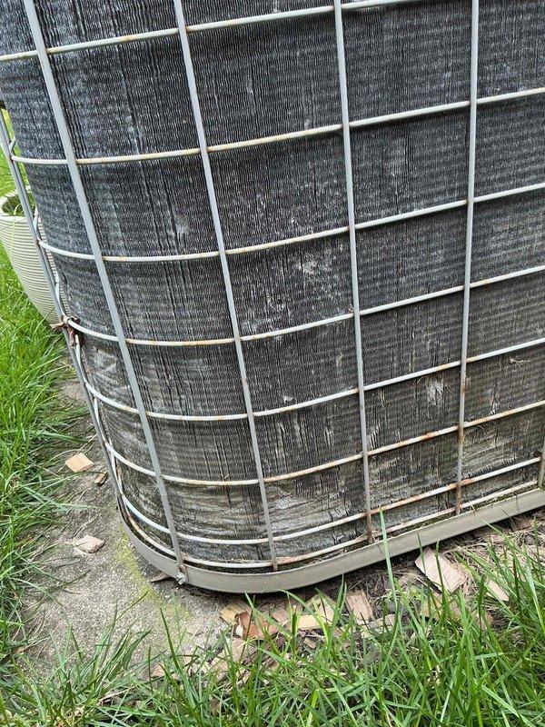 Completed spring preventative maintenance on residential air conditioning system per comfort plan agreement. Outdoor condenser unit exhibited heavy accumulation of dirt, dust, and debris on coil fins prior to service. Performed thorough cleaning of condenser coils, inspected refrigerant lines with existing orange cable tie securing, and verified proper unit operation. System tested and confirmed operational following maintenance procedures.